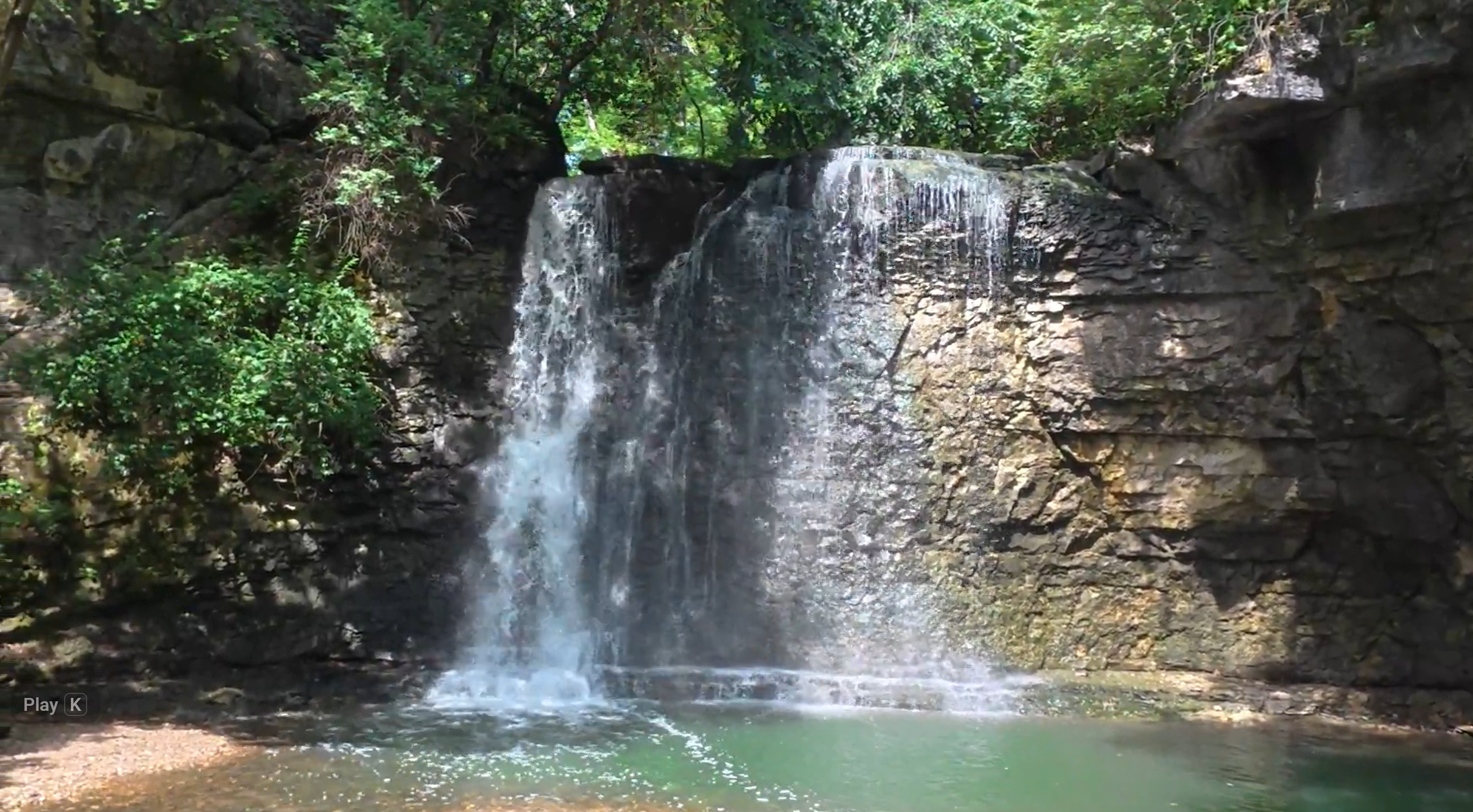 Hayden Run Falls cascading over a limestone cliff into a pool surrounded by green woods